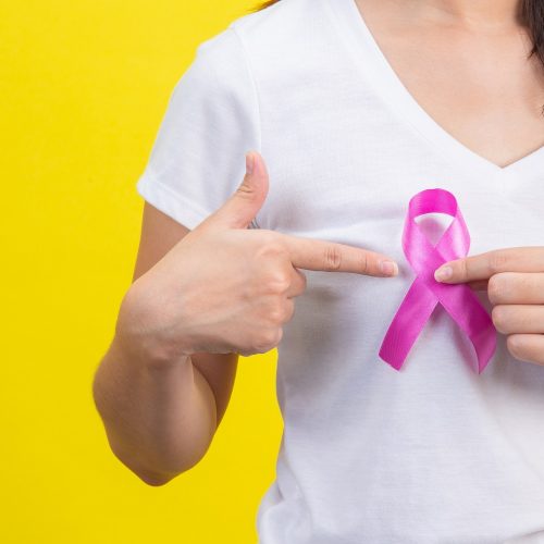 Breast cancer month, a woman in a white T-shirt with a satin pink ribbon on her chest, a symbol for breast cancer awareness campaign in October