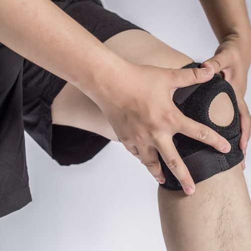 Close-up Of A Man Wearing Knee Brace Over White Background